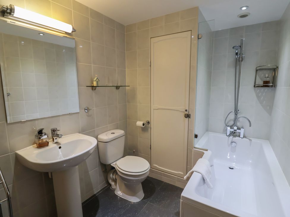 A bathroom with a sink, toilet, bath tub, and mirror at The Dairy in 