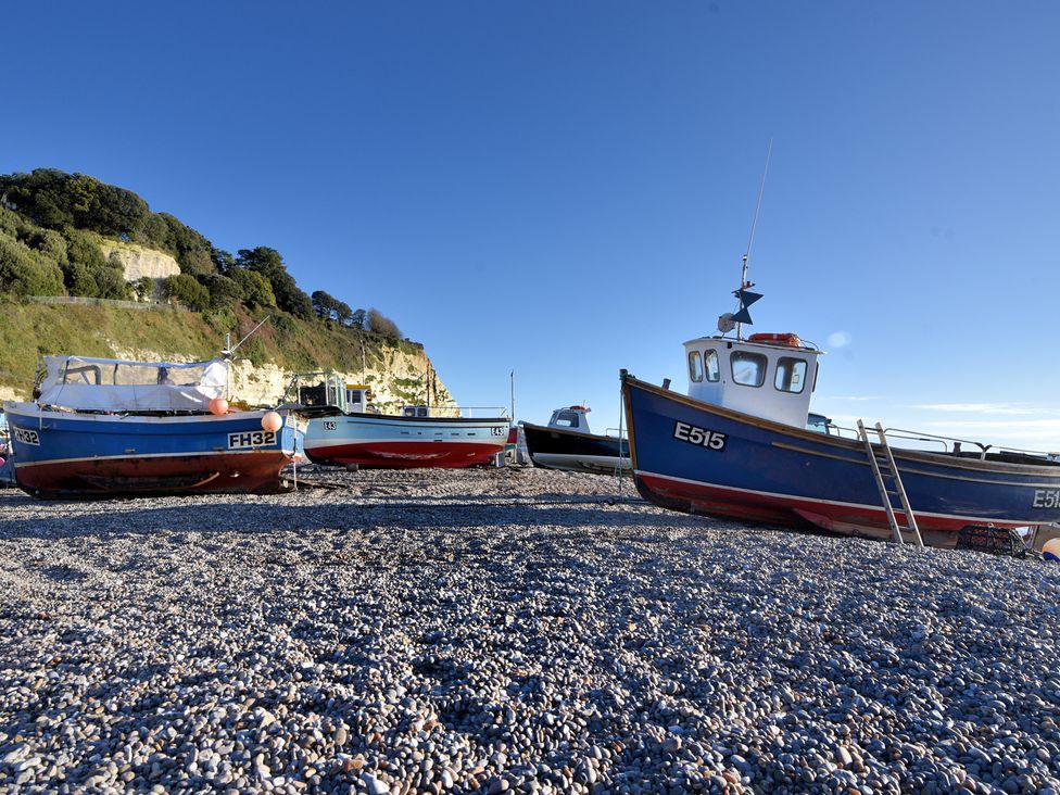 Three boats on a pebbled beach with cliffs in the background at The Dairy