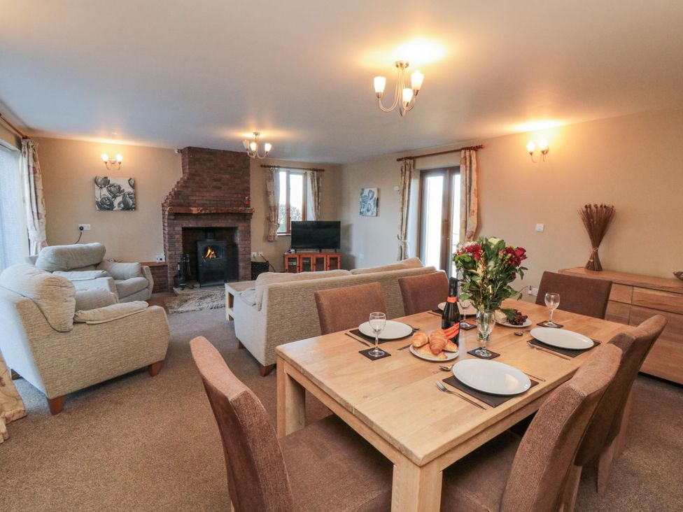 A living room with a dining area featuring a sofa and fireplace at Pasture View Sneatonthorpe near Whitby