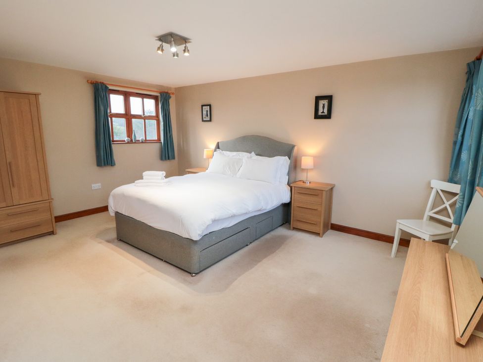 A bedroom with a bed, nightstand, lamp, and window at Pasture View in Sneatonthorpe near Whitby