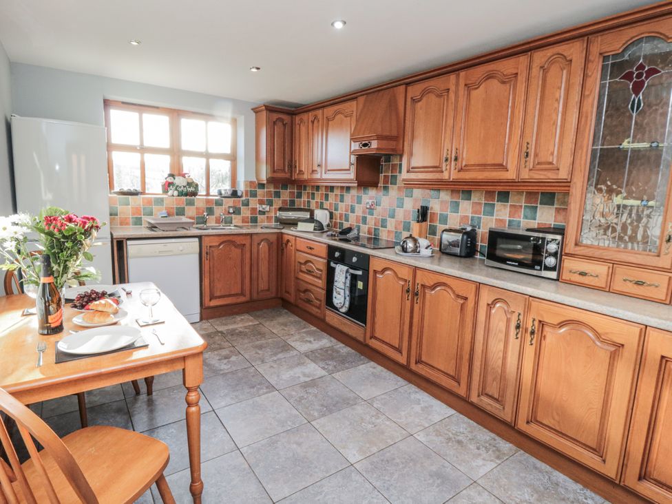 A kitchen with wooden cabinets and a dining table at Beck View in Whitby