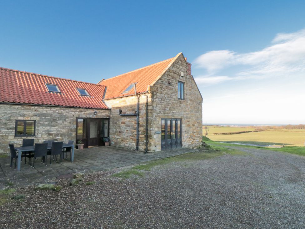 A stone building with a dining area outside at Wheelhouse Cottage in 