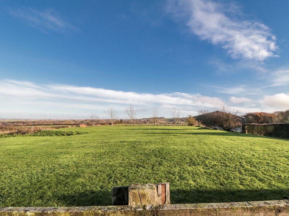 A grassy field with trees and a clear sky at Wheelhouse Cottage in 