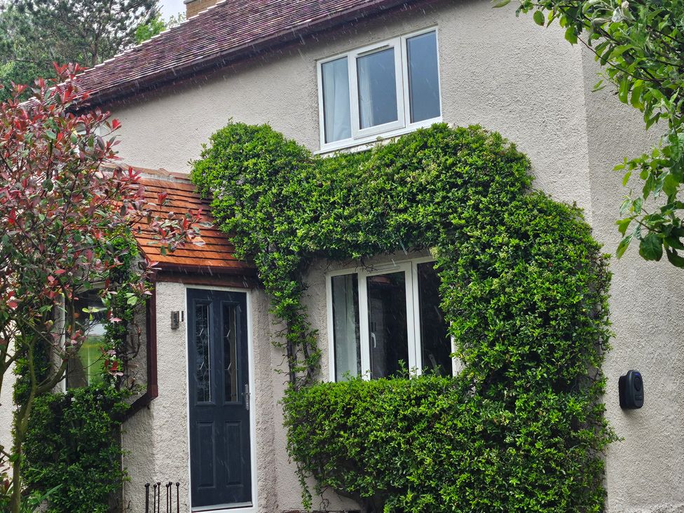 A house with a front door and windows surrounded by shrubbery at Rockhurst Farm Matlock