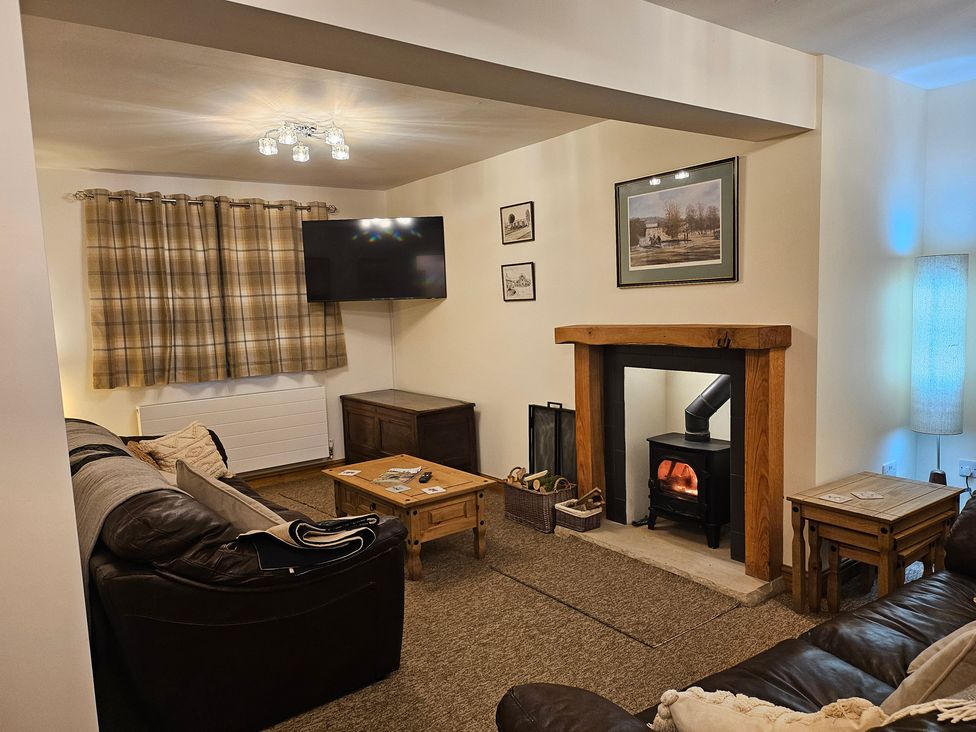 A living room with a sofa, TV, and fireplace at Rockhurst Farm in Matlock
