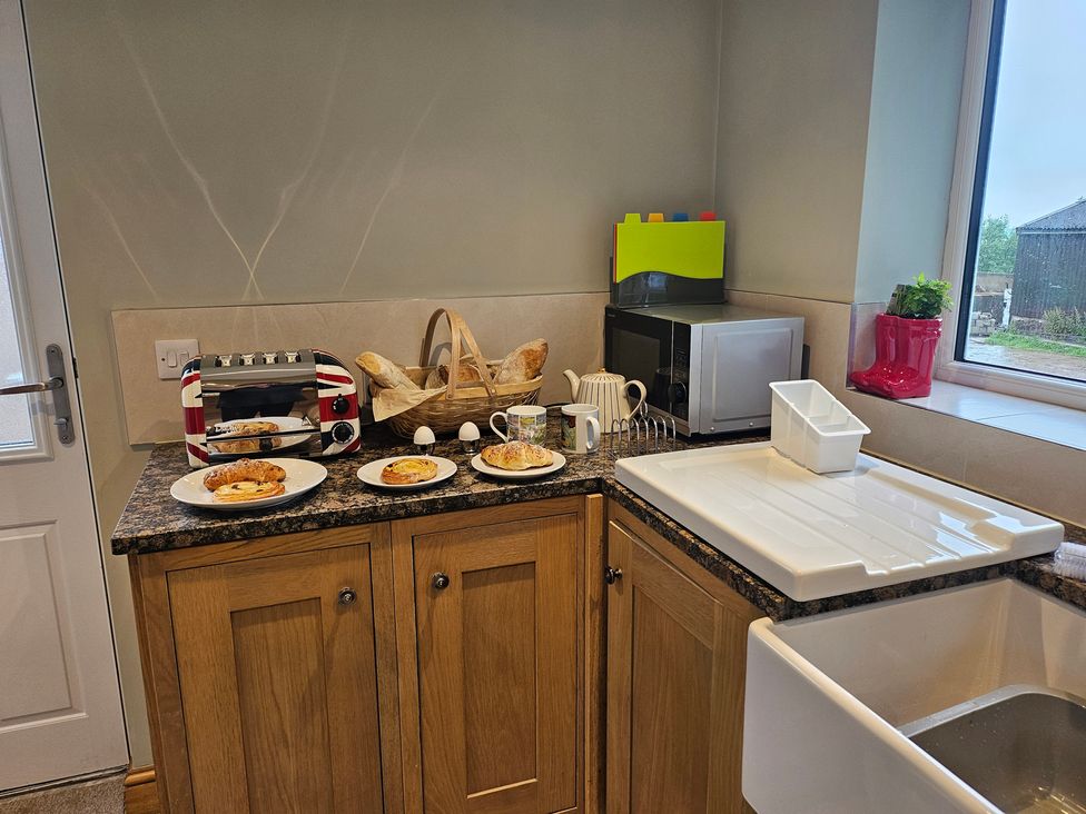 A kitchen counter with a toaster and plates of food at Rockhurst Farm Matlock