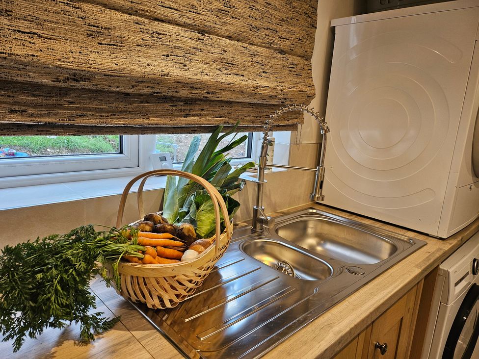 A kitchen with a sink and vegetables in a basket at Rockhurst Farm in Matlock