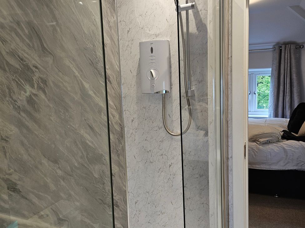 A bathroom with a shower and a view of a bed at Rockhurst Farm Matlock