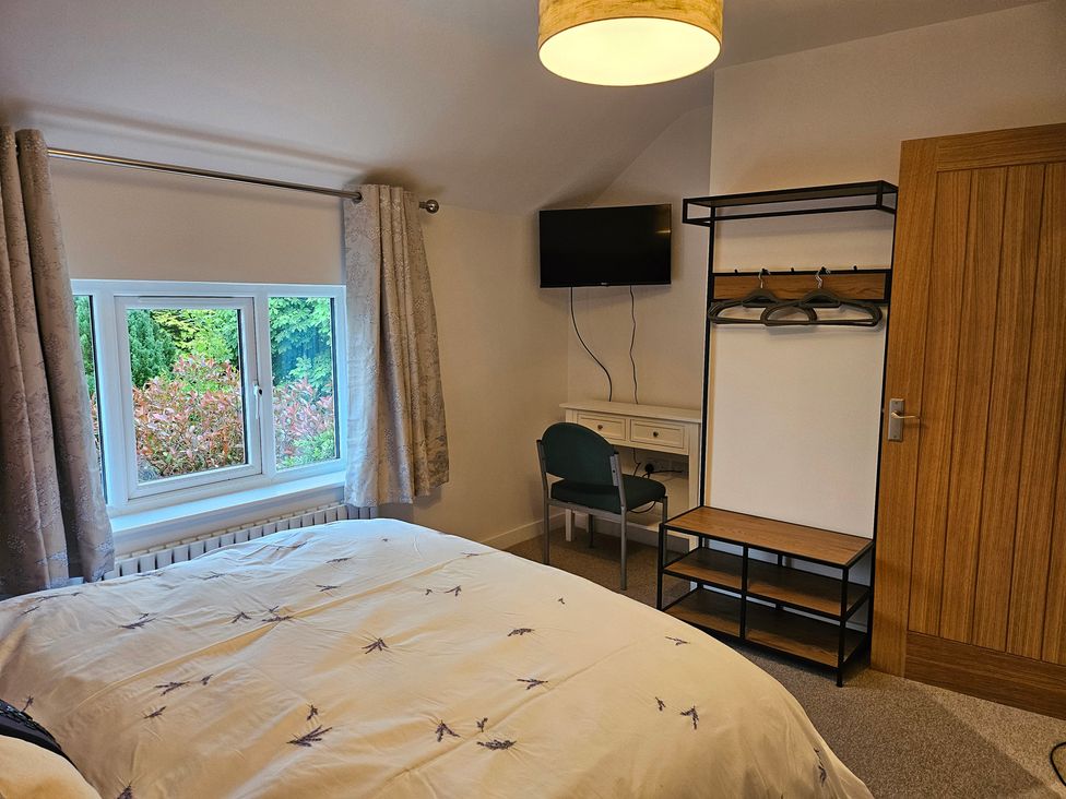 A bedroom with essential furniture and a window overlooking the garden at Rockhurst Farm in Matlock