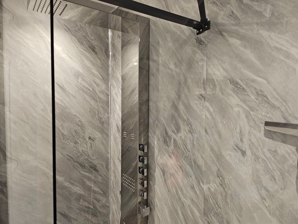 A shower with glass door and control panel at Rockhurst Farm in Matlock