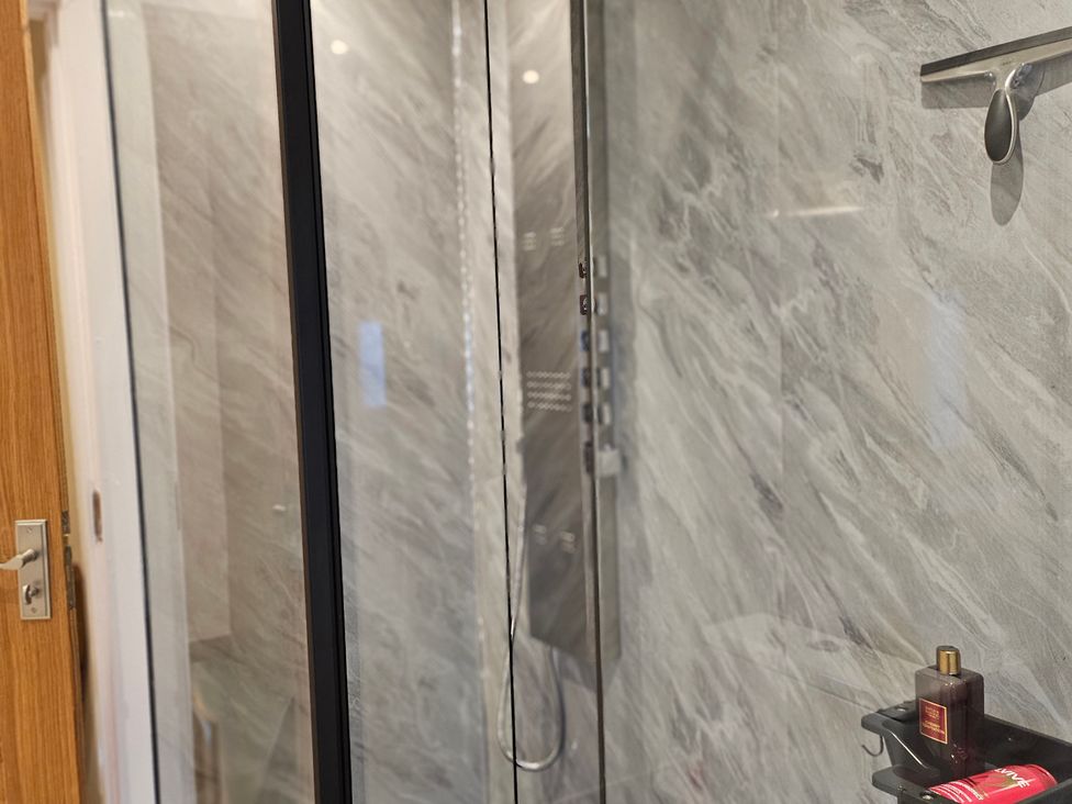 A shower with glass door and shelf in the bathroom at Rockhurst Farm in Matlock