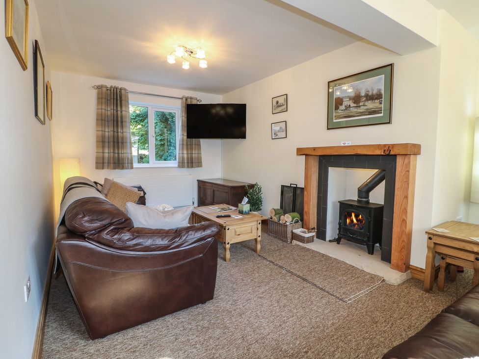 A living room with a fireplace and television at Rockhurst Farm near Winster