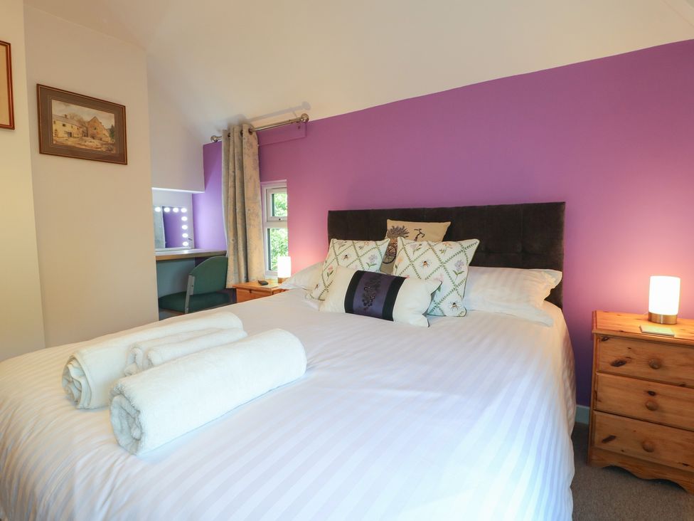 A bedroom featuring a bed with pillows and a mirror area at Rockhurst Farm near Winster