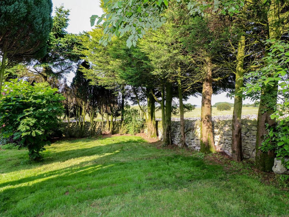 A garden with trees and a stone wall at Rockhurst Farm near Winster