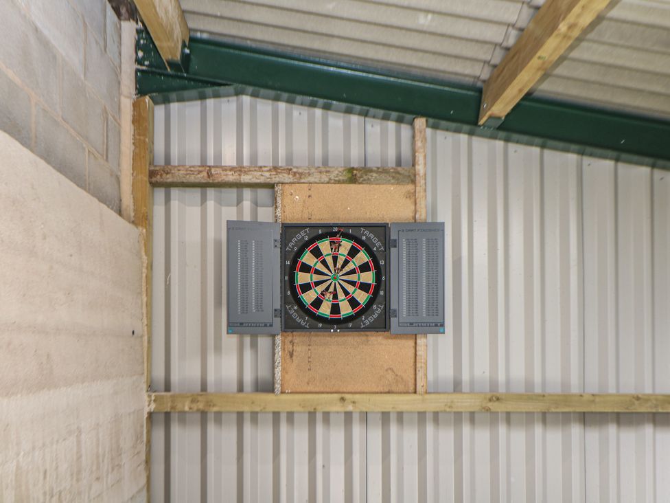 A dartboard with a scoreboard on the wall in the game room at Rockhurst Farm near Winster