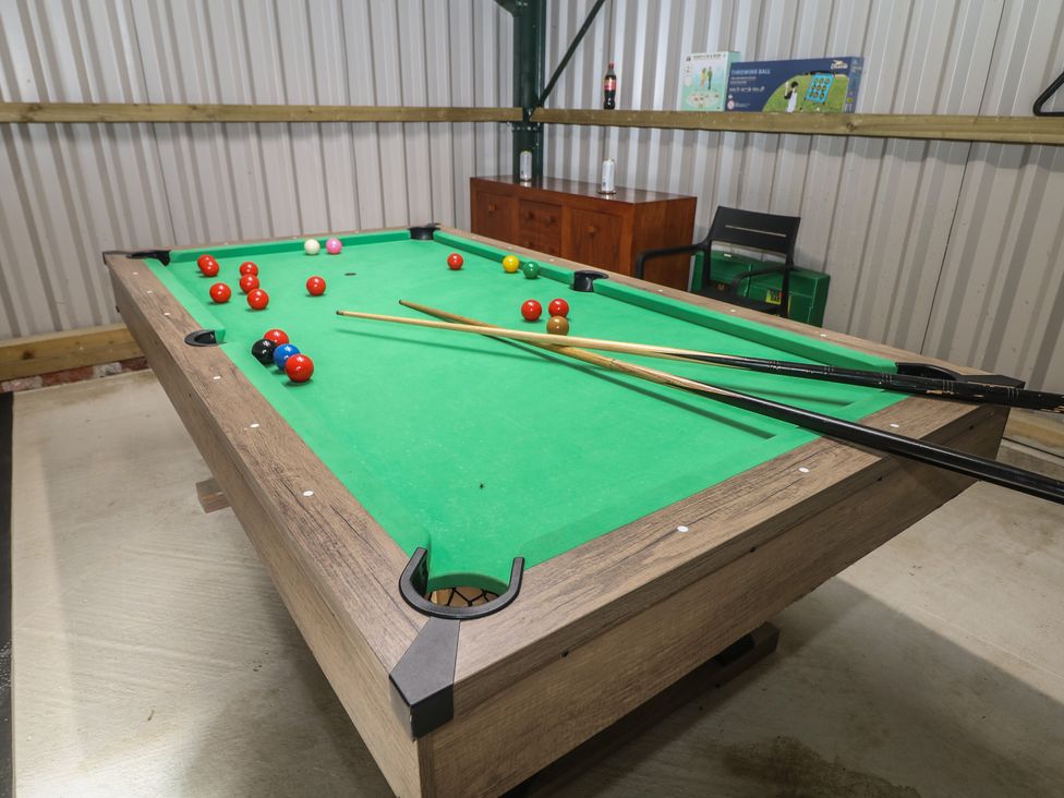 A pool table with cue sticks and balls in a recreation room at Rockhurst Farm near Winster