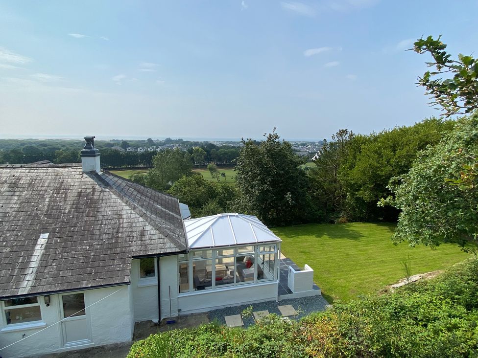 A garden with a conservatory and view of the field at Hafod Y Graig Morfa Bychan