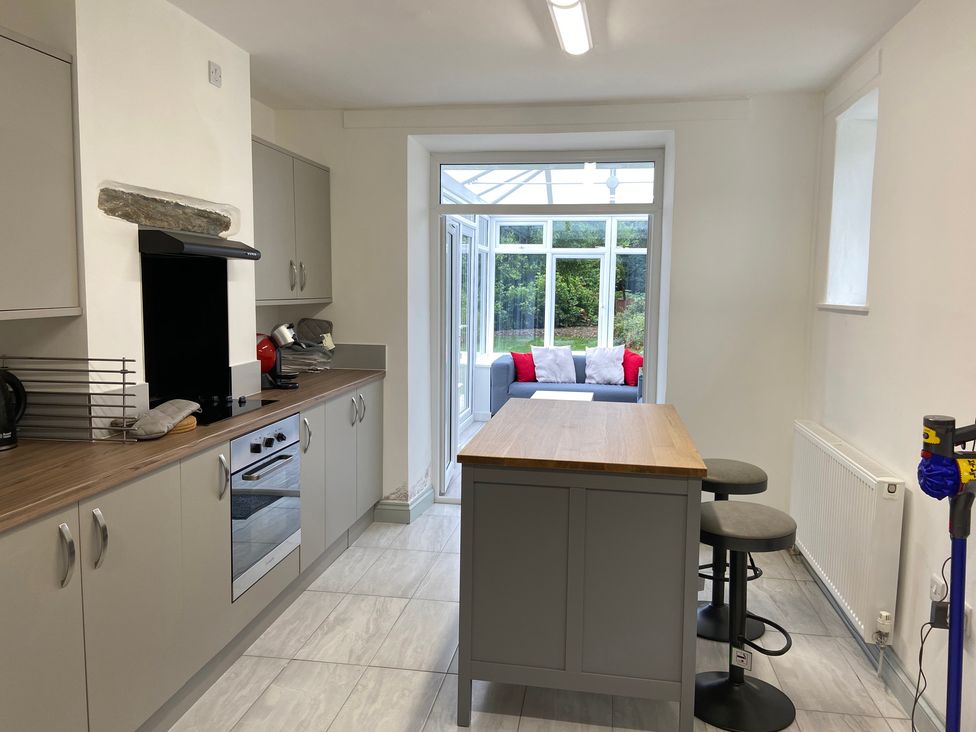 A kitchen with an island and stools at Hafod Y Graig in Morfa Bychan