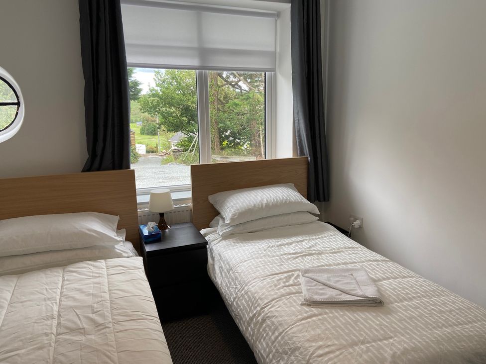 A bedroom with two single beds and a window at Hafod Y Graig Morfa Bychan