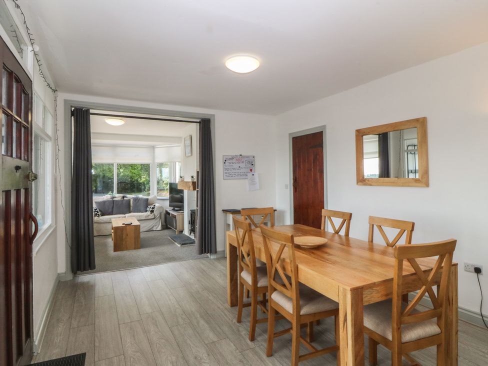 A dining room with a wooden table and chairs at Seaview Hafod Y Graig in Morfa Bychan