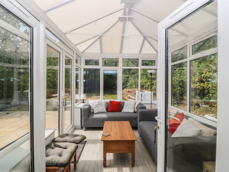 A conservatory with a sofa and coffee table at Seaview Hafod Y Graig in Morfa Bychan