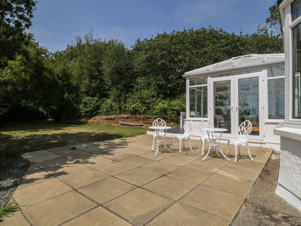 A garden with a table and chairs near a conservatory at Seaview Hafod Y Graig Morfa Bychan
