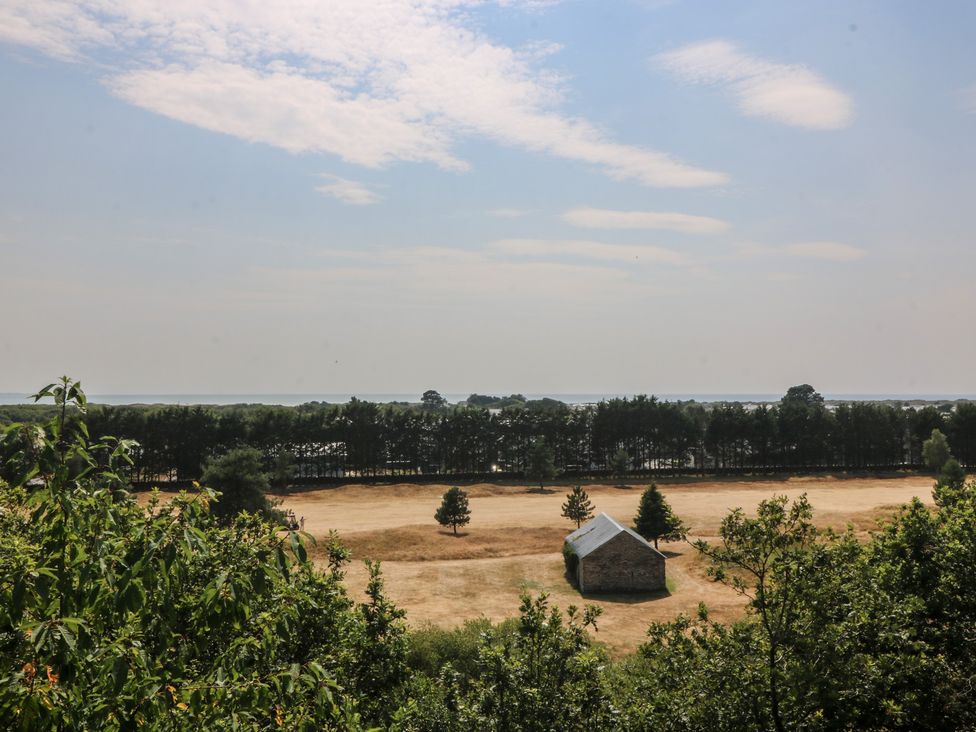 A barn in a field with trees under a blue sky at Seaview Hafod Y Graig Morfa Bychan