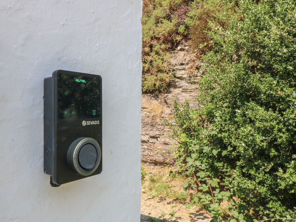 An electric vehicle charger mounted on a wall with surrounding plants at Seaview Hafod Y Graig Morfa Bychan