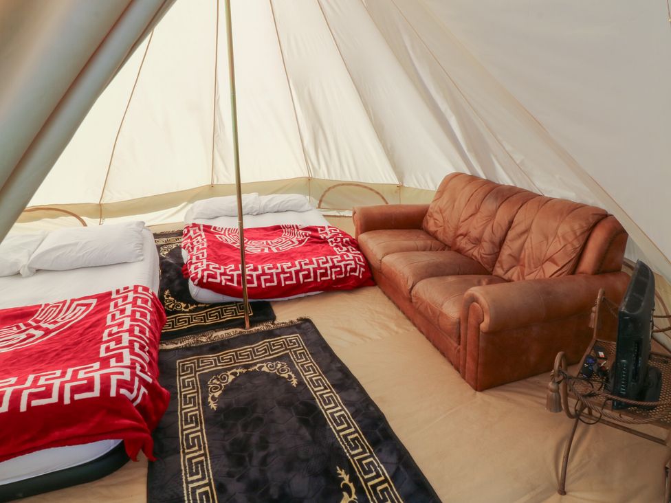 An indoor arrangement with beds and furniture in a tent at Bell Tent Two 