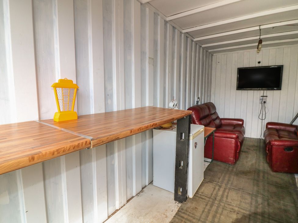 A seating area with a couch, table and tv at Bell Tent Three