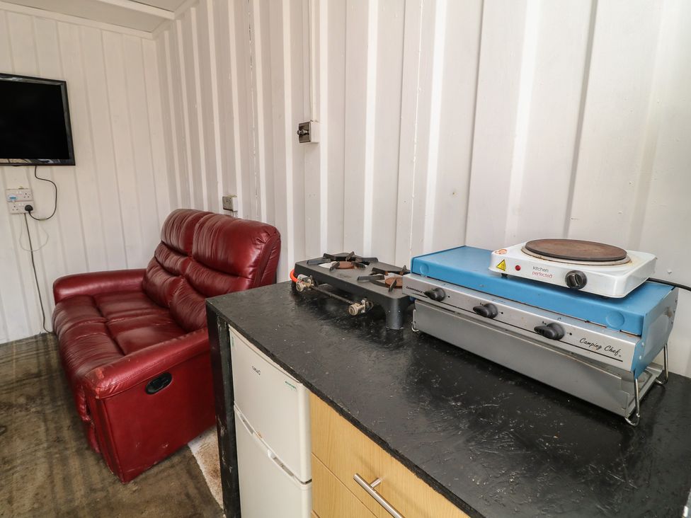 A living room with a sofa and kitchen appliance at Bell Tent Three 