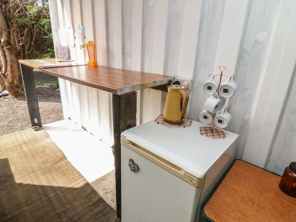 An outdoor kitchen with a table and fridge at Bell Tent Three
