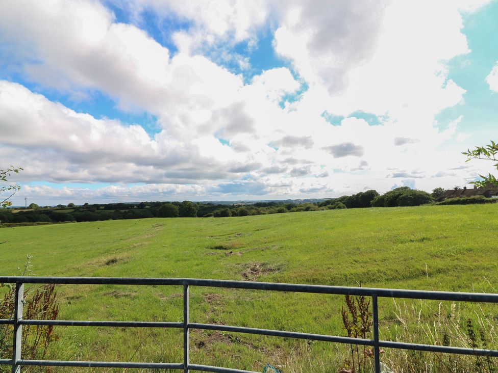 A view of a grassy field with clouds and trees at Bell Tent Three