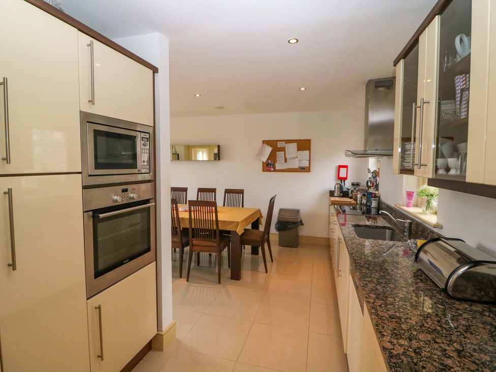A kitchen with appliances and a dining table at 25 Ring of Kerry Holiday Cottages Kenmare