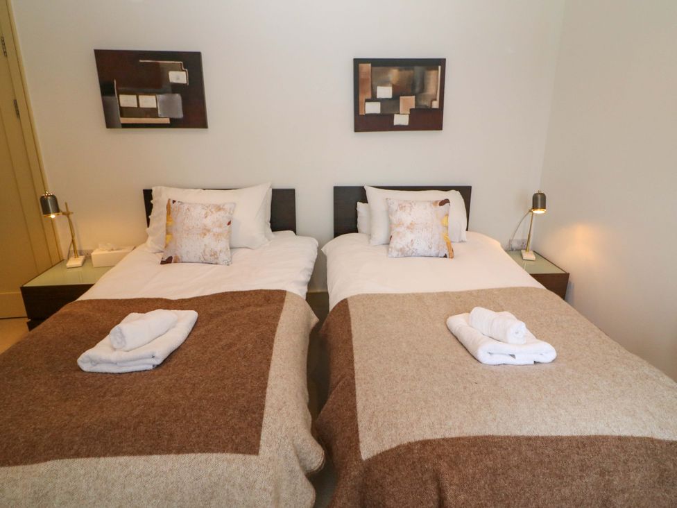 A bedroom with twin beds and bedside tables at 25 Ring of Kerry Holiday Cottages in Kenmare