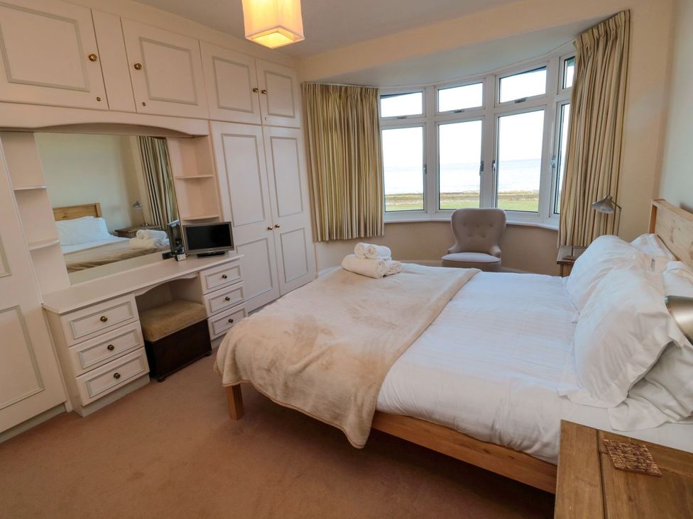 A bedroom with a bed and dresser at Glen Avon in Seahouses