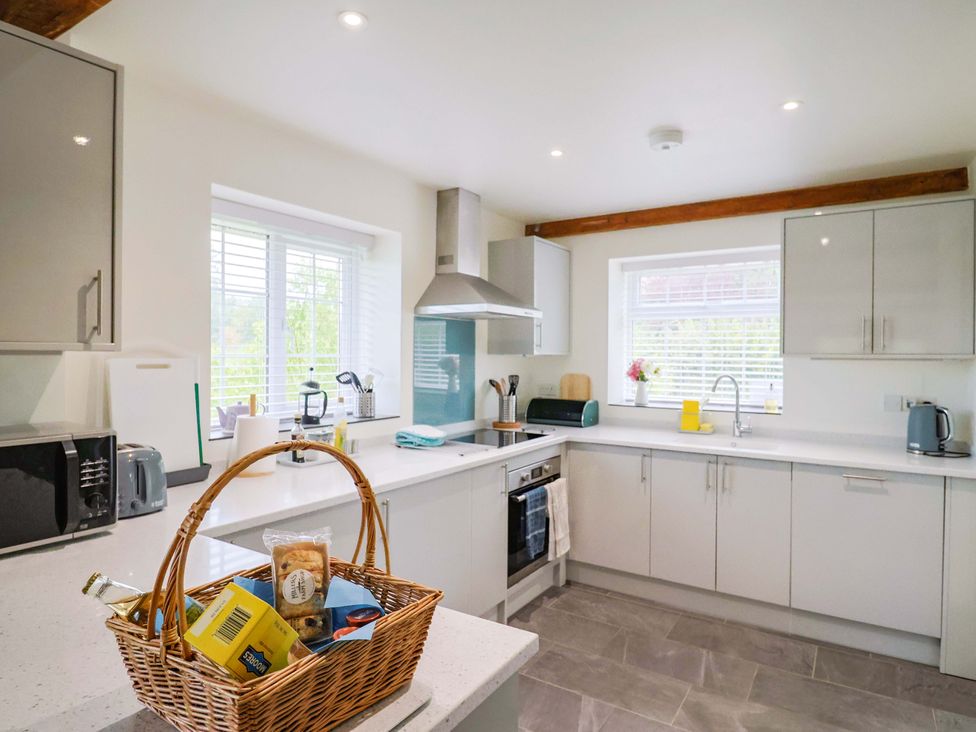 A kitchen with appliances and a basket of food items at The Cottage Middle Westwater