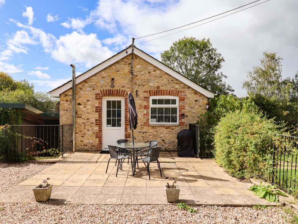 An outdoor area with a stone wall, table and chairs at The Cottage Middle Westwater in Westwater Nr Axminster