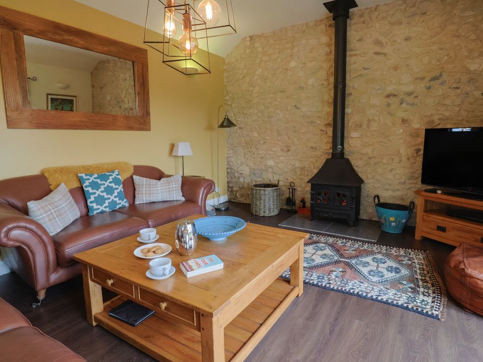A living room with a sofa, coffee table, and television at The Sundowner in Wyke Nr. Axminster