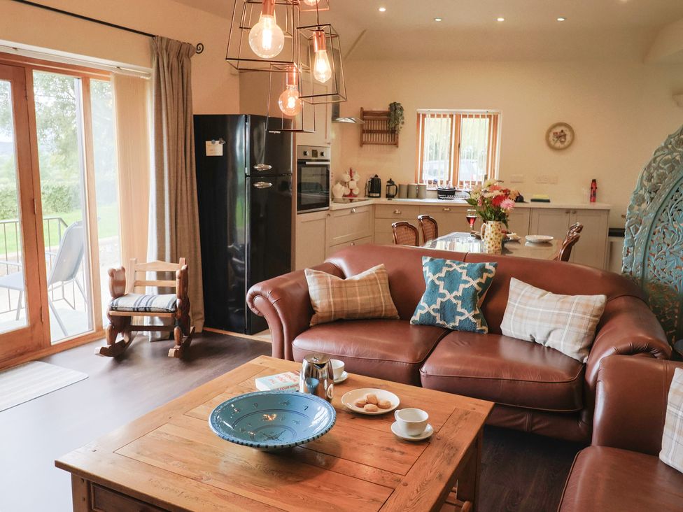 A living room with a sofa and kitchen area at The Sundowner in Wyke Nr. Axminster
