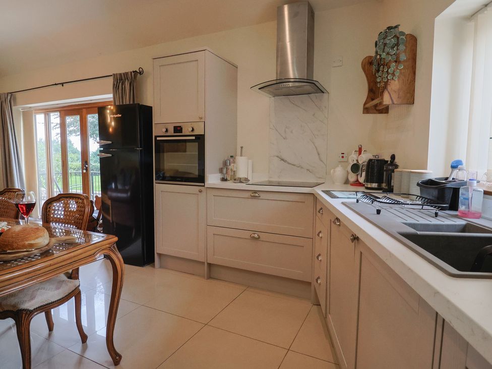 A kitchen with a table and chairs and a refrigerator at The Sundowner in Wyke Nr. Axminster