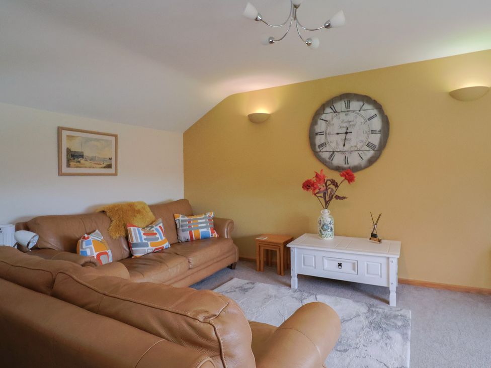 A living room with a sofa and clock at The Granary in Wyke Nr Axminster