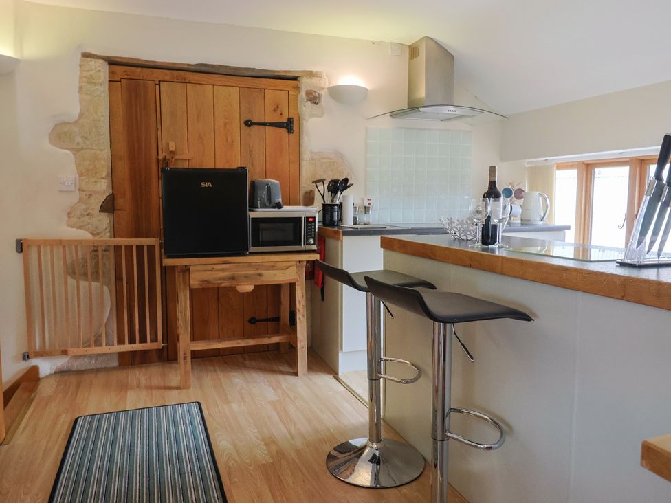 A kitchen with refrigerator, microwave and bar counter at The Granary Wyke Nr Axminster