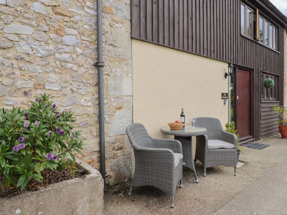 A table and chairs with a wine bottle and glasses at The Granary in Wyke Nr Axminster