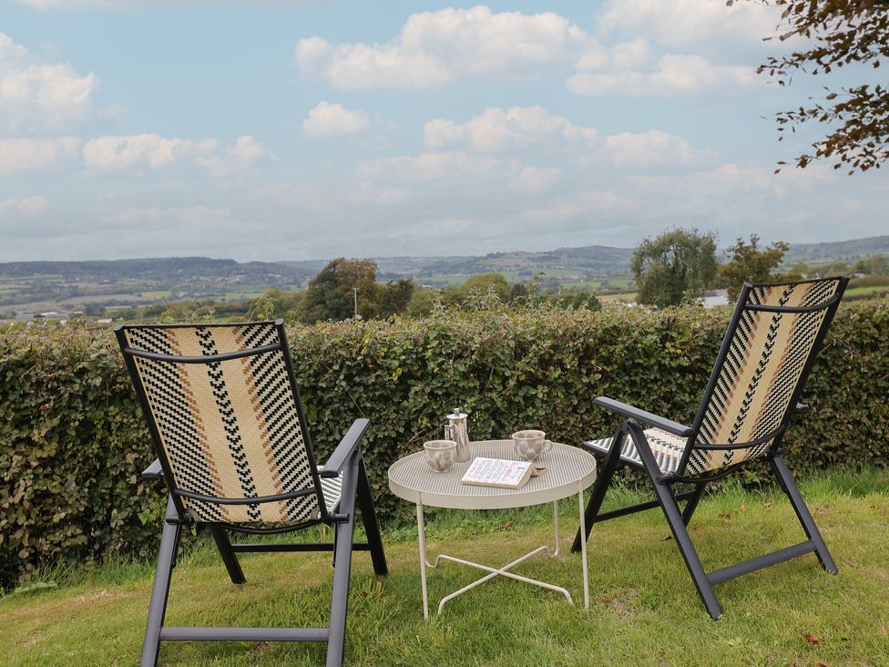 Two chairs and a table with a coffee pot and cups overlooking a view at The Granary in Wyke Nr Axminster