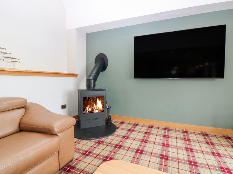A living room with a fireplace and television at The Old Kipper Hoose in Banff
