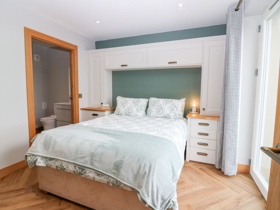 A bedroom with a bed and a doorway leading to a bathroom at The Old Kipper Hoose in Banff