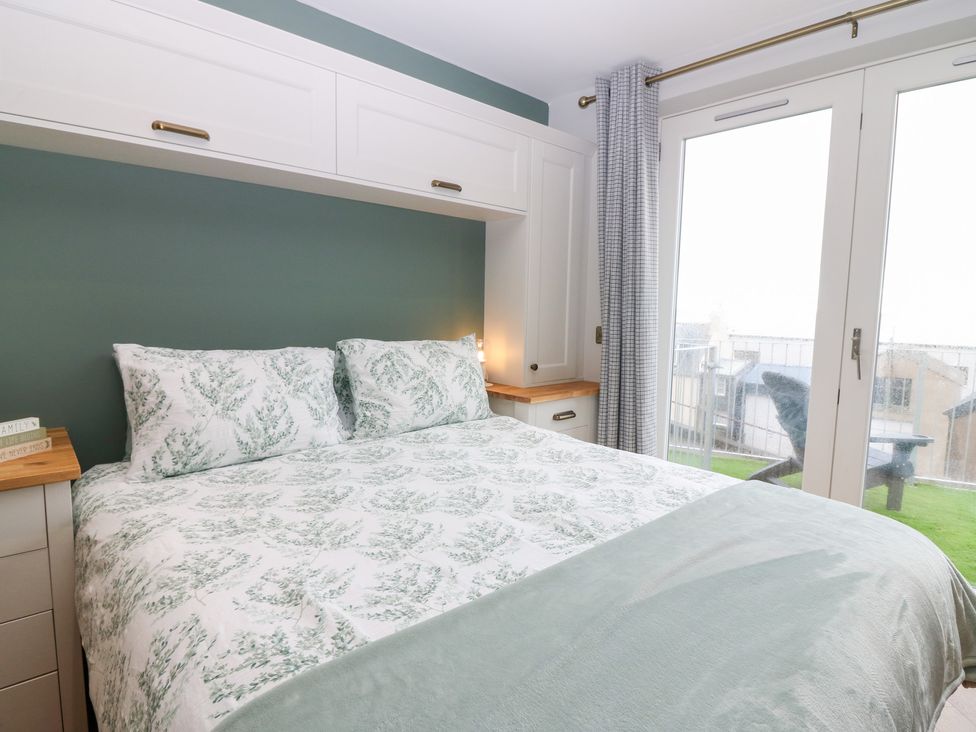 A bedroom with a bed and patio doors at The Old Kipper Hoose in Banff