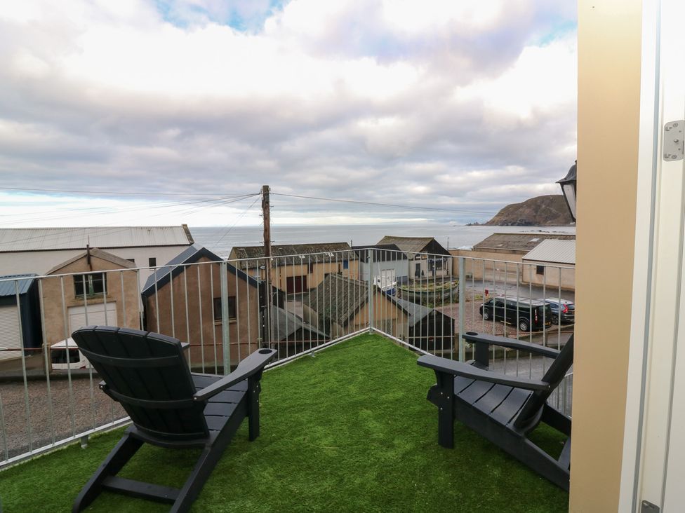 An outdoor seating area with chairs overlooking the ocean at The Old Kipper Hoose in Banff