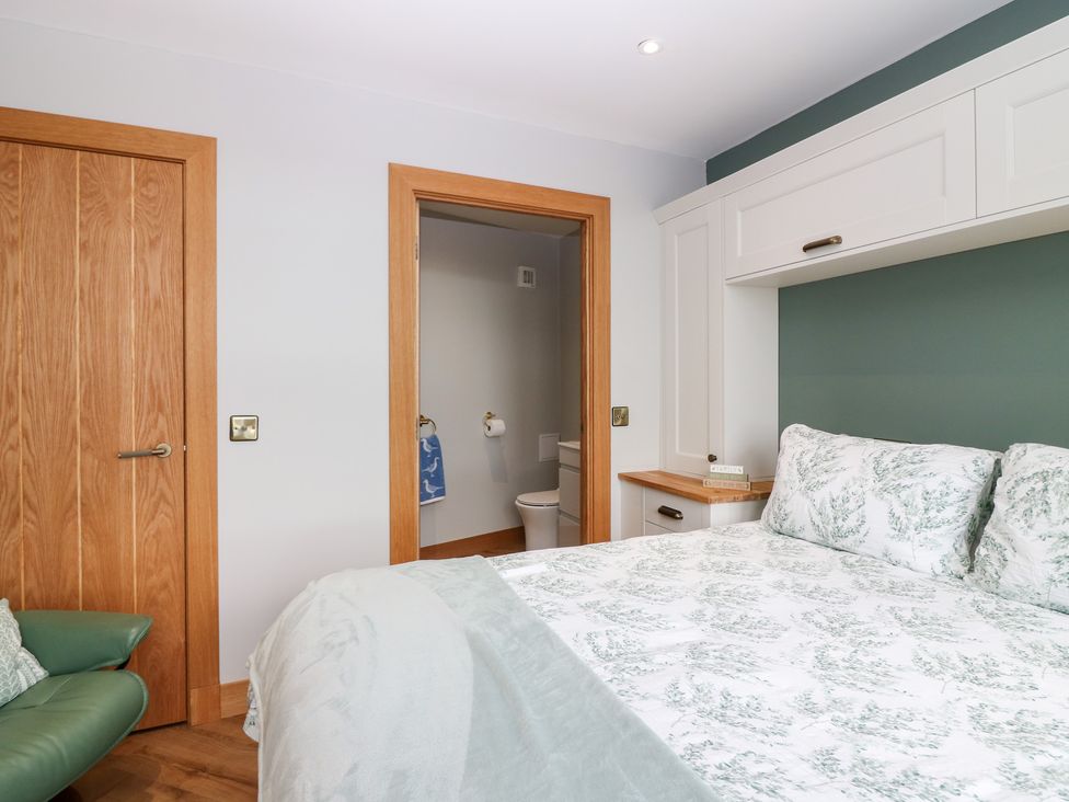 A bedroom with a bed and a door leading to a bathroom at The Old Kipper Hoose in Banff